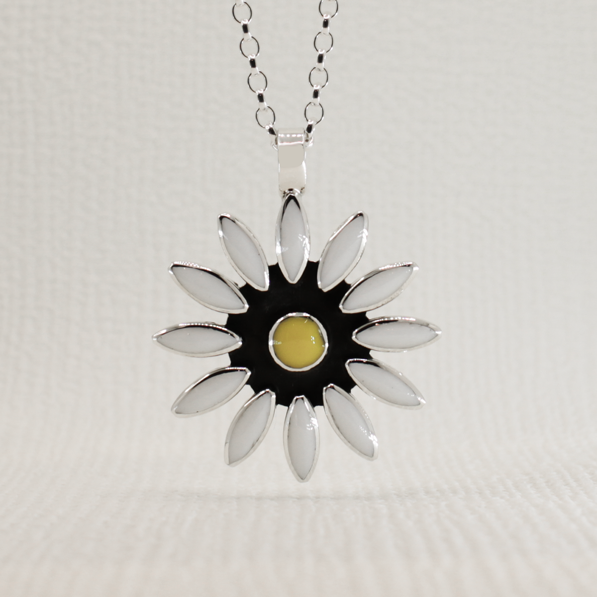 This gorgeous Sleveen White Resin Daisy Silver Pendant is sure to turn heads! It measures 32mm in diameter and 46mm from the top of the bail and is crafted with .925 silver. The bail fits up to 7mm chain and comes with an adjustable 2.5mm silver roll chain that can be adjusted from 16" to 18"!
